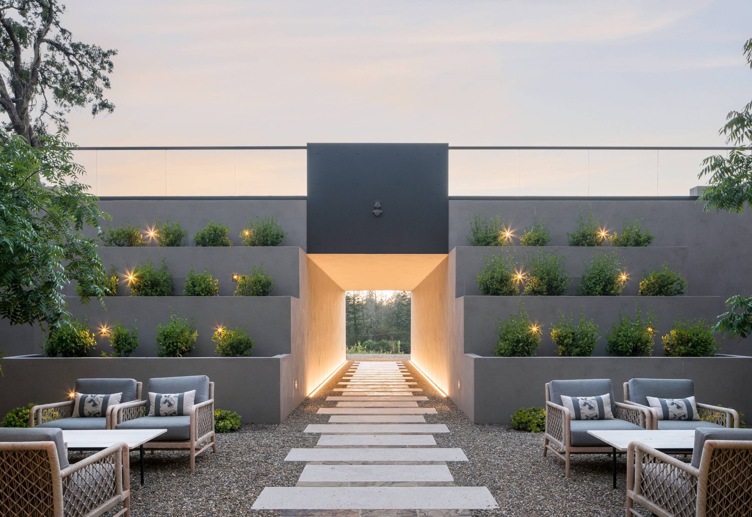 outdoor patio with dramatic lighting, terraced garden, and view of forest in background
