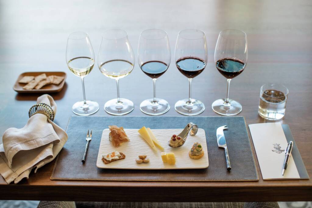 Place setting for a tasting, with cheese, charcuterie, and 5 wines.