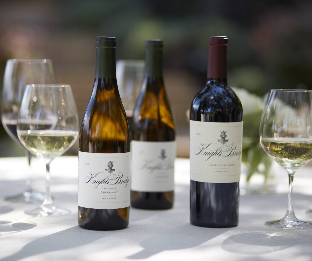 outdoor table set with wine bottles, glasses, and a flower arrangement
