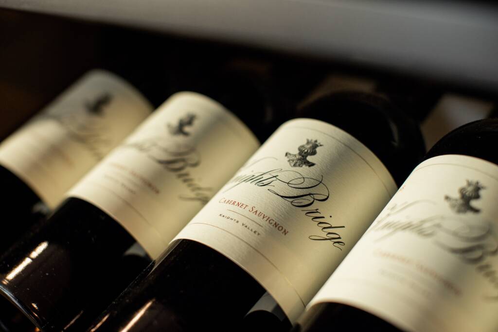 Array of Cab Sauv bottles lined up on shelf.